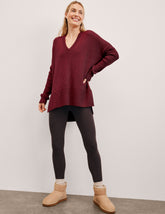 woman wearing a red v-neck sweater sweater against a plain background.